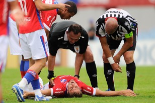 El árbitro Gustavo Siegler brinda los primeros auxilios a Iván Alonso tendido en la cancha.