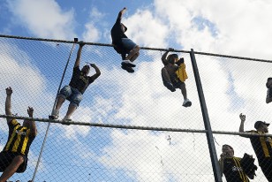 Hinchas aurinegros trepados en la cima del tejido perimetral olímpico.